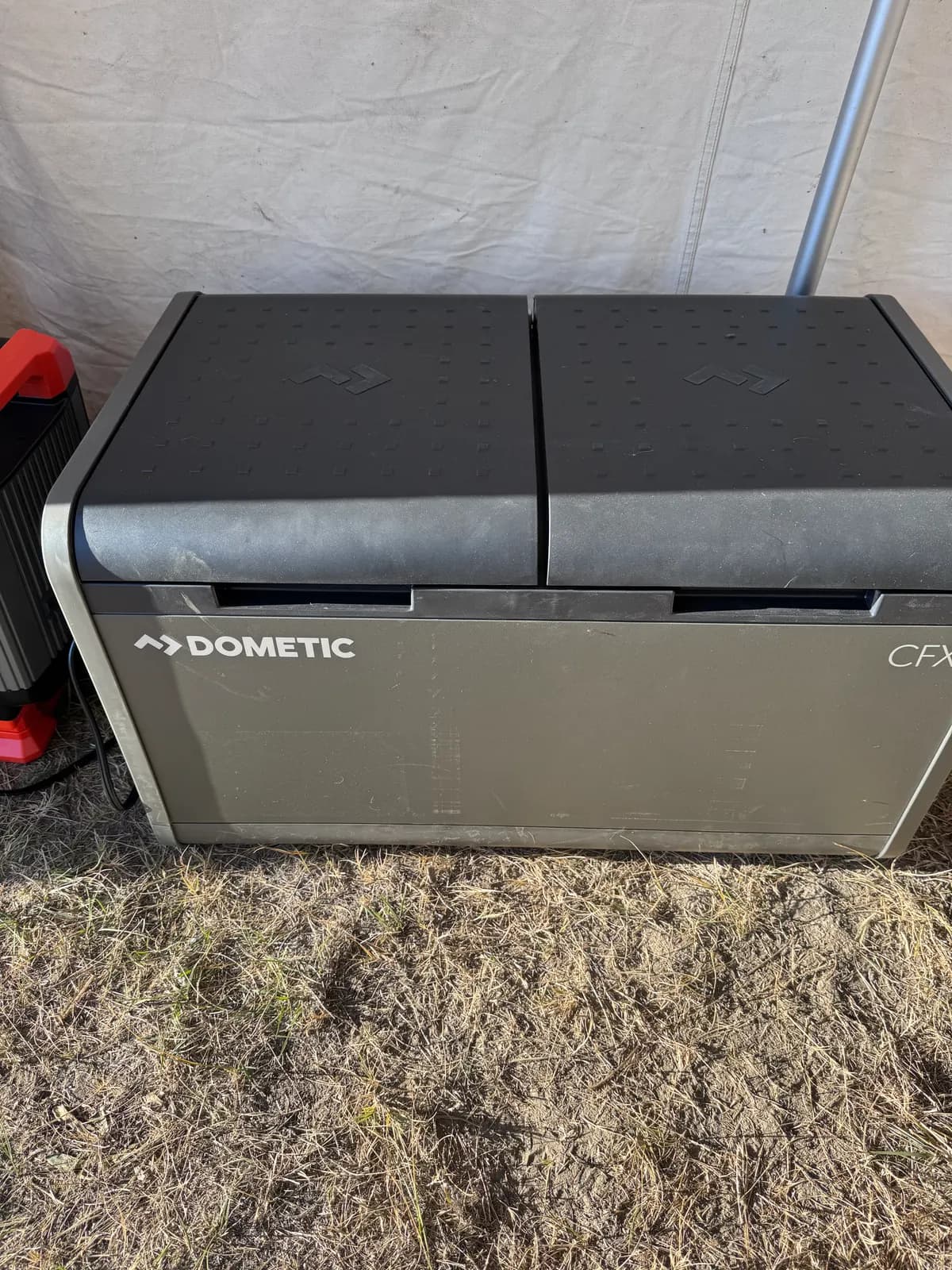 A Dometic CFX electric cooler beside a power station.